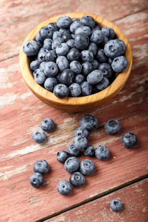 organic blueberries in a wooden plate and sprinkled on a table, on a wooden background. place for...