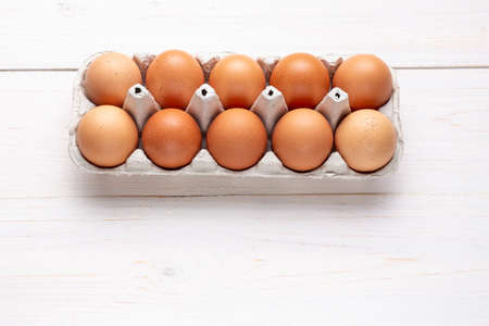 farm red chicken eggs in a cardboard tray on a wooden background. place for text