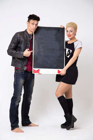 The guy and the girl are holding a notice board on a white background. Place for the text of invitations for the holidays.の写真素材