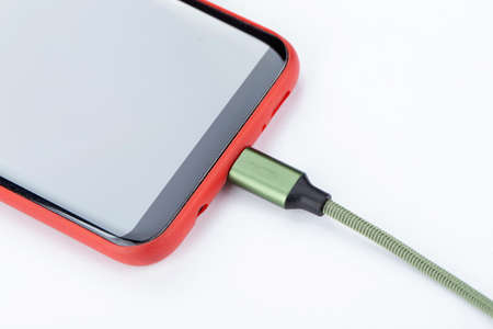 Smartphone Connects to Charger through USB Cable on a white background.の写真素材