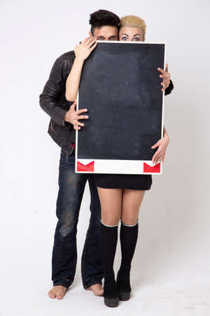 The guy and the girl are holding a notice board on a white background. Place for the text of invitations for the holidays.の写真素材