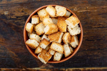 croutons beer snack crackers in a plate on a brown wooden background. view from above