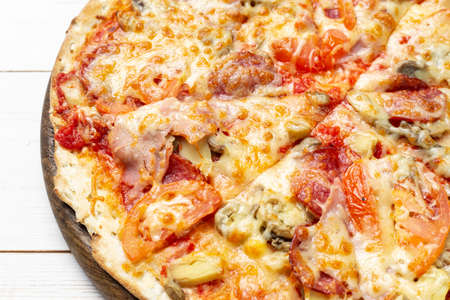 Delicious simple pizza with tomatoes, mozzarella and bacon on white wooden background. Space for text.の写真素材