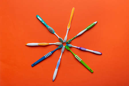 Toothbrushes on orange background. Hygiene of the oral cavity. Top view.