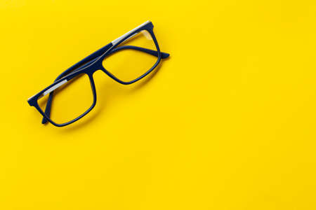 Fashionable glasses in blue frames for vision on a yellow background. Health concept. The medical field that studies the eyes.の写真素材