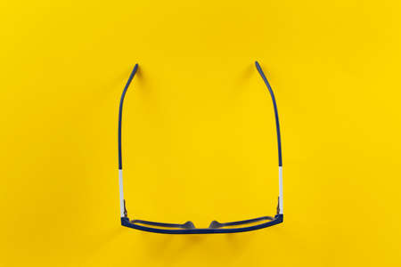 Fashionable glasses in blue frames for vision on a yellow background. Health concept. The medical field that studies the eyes.の写真素材