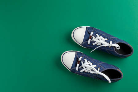 New blue gumshoes on green background with copy space.の写真素材