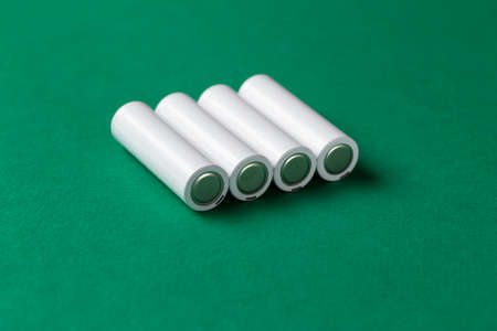 Rechargeable AAA batteries in white on a green background. Place for text. Green energy concept.
