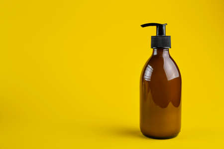 Cosmetics containers mockup. Glass cosmetic container with dispenser on a yellow background.の写真素材