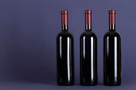 Three corked bottles of red wine on a lilac background. With space for text. Wine tasting and drinking culture concept.の写真素材