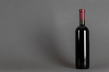 Closed bottle of wine on a gray background. Wine drinking culture concept. Space for text.の写真素材