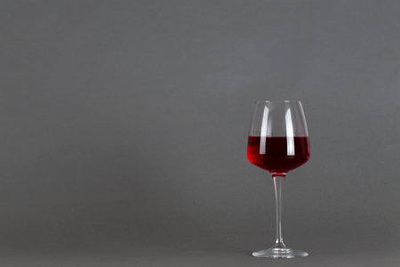 Glass of red wine on a gray background. Wine drinking culture concept. Space for text.の写真素材