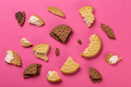 Pieces of chocolate chip cookies and biscuits with filling on a pink background close-up. Top view.