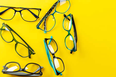 Many stylish glasses on a yellow background. Health, style and business concept. Eyesight correction. Space for text.の写真素材