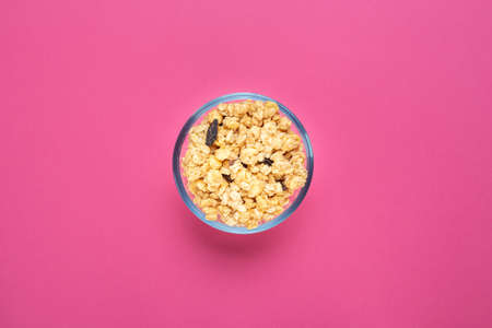 Healthy breakfast. Oatmeal with dried grapes in a glass bowl on a pink background. Musli is healthy food. Space for text. Top view.の写真素材
