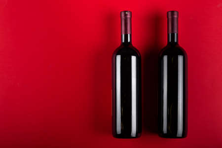 Two bottles of red wine on a red background. Romantic mood. Space for text. Top view.の写真素材