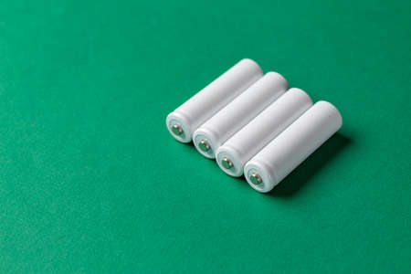 Rechargeable AAA batteries in white on a green background. Place for text. Green energy concept.の写真素材
