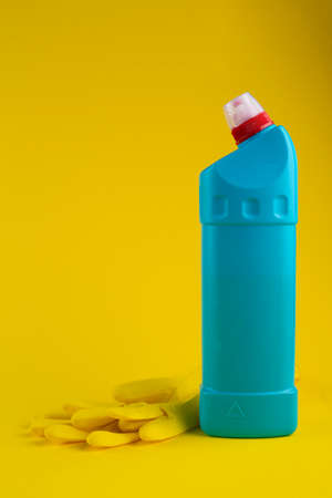 Blue bottle of cleaning agent and rubber gloves on a yellow background. Cleanliness concept. Space for text.の写真素材