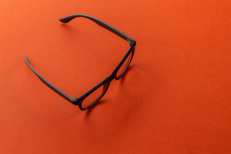 Eyeglasses on orange background, myopia or presbyopia. Eyesight correction. Fashion accessories.の写真素材
