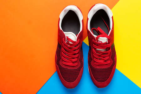 A pair of sports shoes on a colorful background. New sneakers on multi-colored background, copy space. Casual fashionable sneakers red colors. Style concept.の写真素材