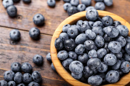 Freshly picked blueberries in wooden bowl on a wooden table. Healthy fruits.の写真素材