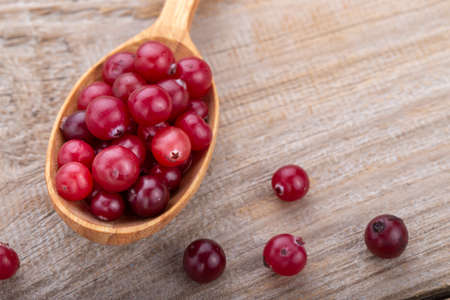 Ripe cranberries in a wooden spoon. Healthy food concept.