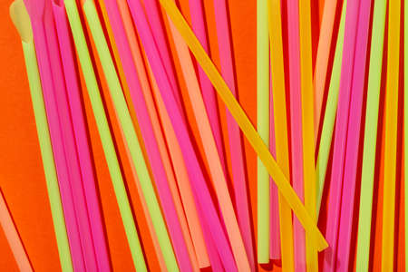 Colored tubules for juice and cocktails on orange background. Cocktail parties. Space for text. Top view.の写真素材