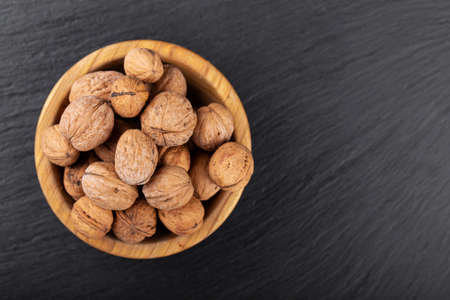 Walnut in wooden bowl on black table