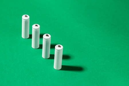 White AA batteries on a green background. Space for text. Recycling of rechargeable NiMH batteries.の写真素材