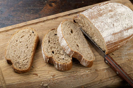 Fresh bread slice and cutting knife on rustic table