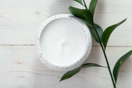 Composition with a candle and a sprig of a plant on a white table. Home interior. Space for text.の写真素材