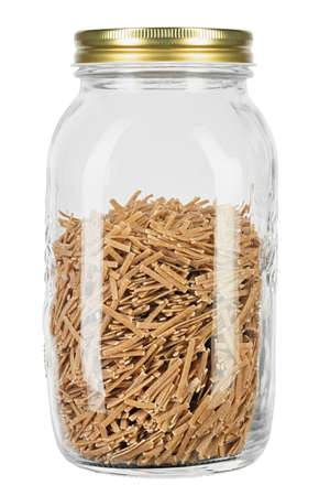 Glass jar filled raw pasta isolated on white background.の写真素材