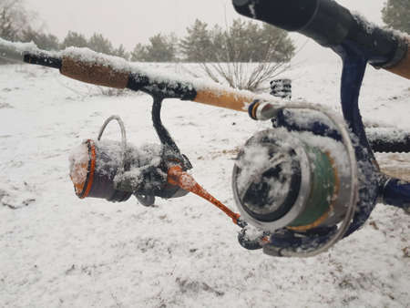 Fishing on the feeder, in the river. Fishing rod and reel close-up. The fishing tackle was covered with snow.の写真素材