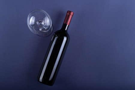 Bottle of red wine without a label and a glass empty on a purple paper background. Mockup drink with place for you label and text. Space for text. Top view.の写真素材