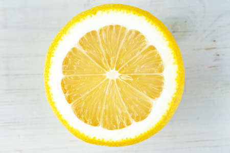 Half a juicy lemon on a white wooden table. Fresh citrus fruits. Top view. Space for text.の写真素材