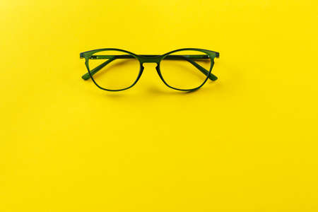 Stylish eyeglasses over yellow background. Optical store, glasses selection, eye test, vision examination at optician, fashion accessories concept. Space for text.の写真素材
