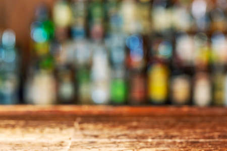 Empty wooden bar counter with defocused background and bottles of restaurant, bar or cafeteria background .For your product display.の写真素材
