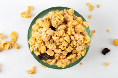 Granola bowl with raisins, nuts. Homemade crunchy granola scattered on white background, top view....