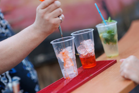 A professional bartender makes cocktails at the bar. Blurred Mojito cocktail in the background. Preparation of alcoholic non-drinks for the holidays.の写真素材