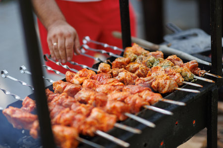 Marinated shashlik preparing on a barbecue grill over charcoal. Shashlik or Shish kebab popular in Eastern Europe. Man cooking marinated shashlikの写真素材