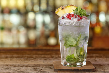 Cocktail with ice, place for text. The cocktail is garnished with cranberries, mint and pineapple. Photo for a cocktail cardの写真素材