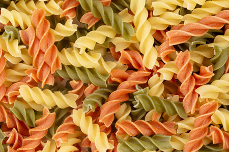 Raw colored pasta fusilli. Uncooked pasta background. Top view.の写真素材