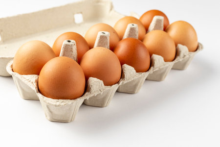 A tray of brown fresh eggs on white background. Eco-friendly egg production. Baking ingredients. Organic chicken eggs - fresh from producer. Top view. Free space for text.の写真素材