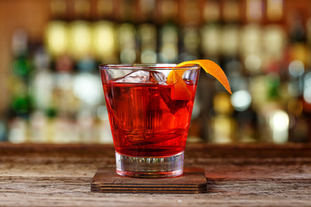 Cocktail Negroni in a nightclub on a shabby wooden bar counter. Cocktail with gin, campari and martini rossoの写真素材