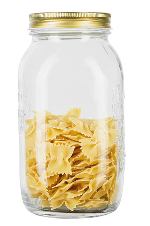Raw farfalle pasta in a glass jar for storing bulk products isolated on white background. File Contains Clipping Path.の写真素材