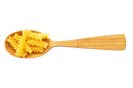 Raw pasta in spoon at white background. Pasta fusilli. Top view. File contains clipping path.の写真素材