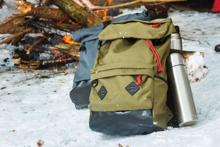 Backpacks in the background of a burning bonfire in the winter forest. Winter trip.の写真素材