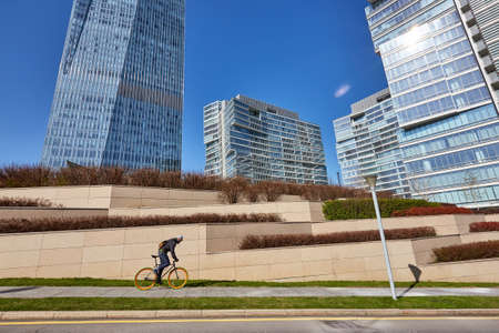 A man is riding a bicycle against the background of high-rise buildings. sunny dayの写真素材