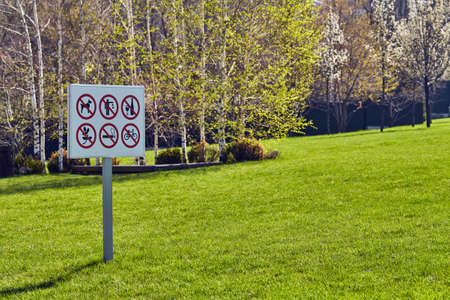 Prohibition signs on a plate installed on a lawn in the city. Spring Park and greeneryの写真素材