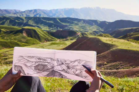 Picture of the mountains in the hands on the background of the landscape. Painting outdoors. Picture of a landscape. Kazakhstan. Mountain spring landscapeの写真素材